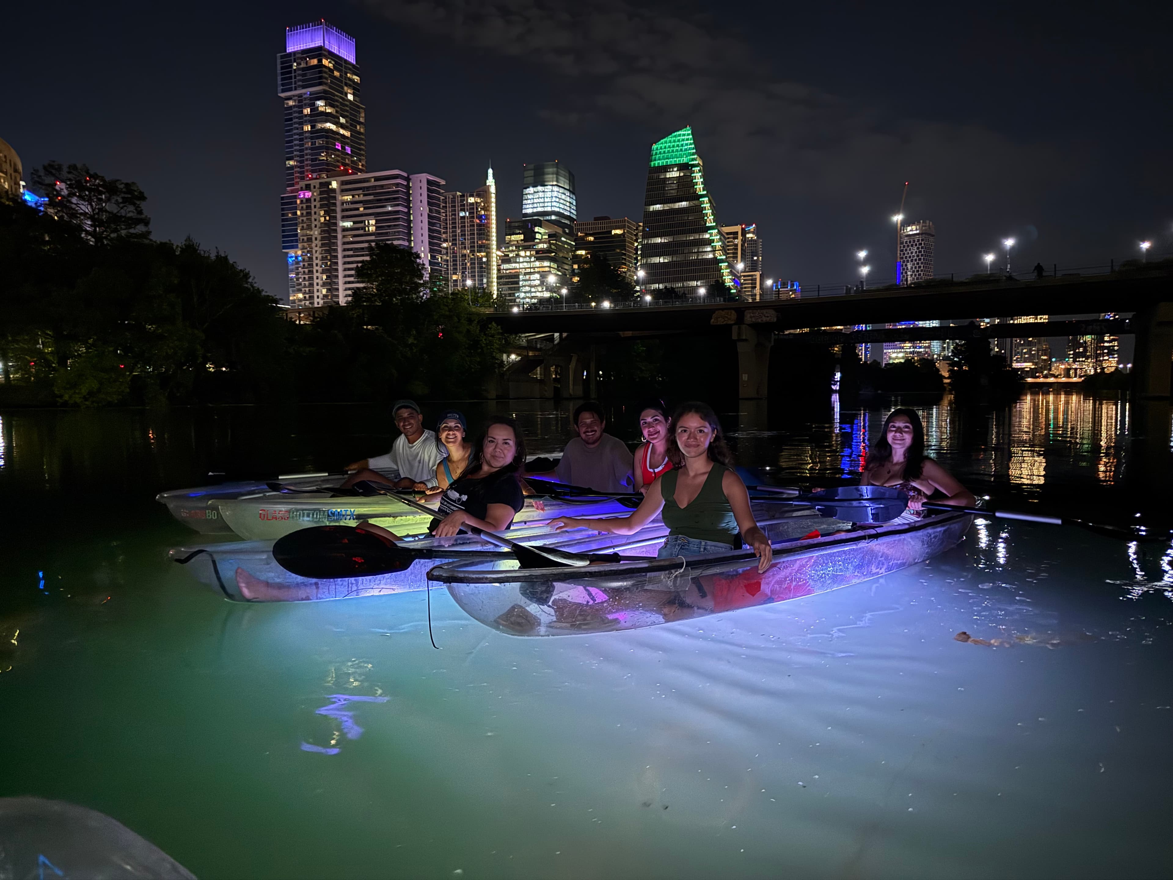 Group glow kayaking with Austin skyline at night